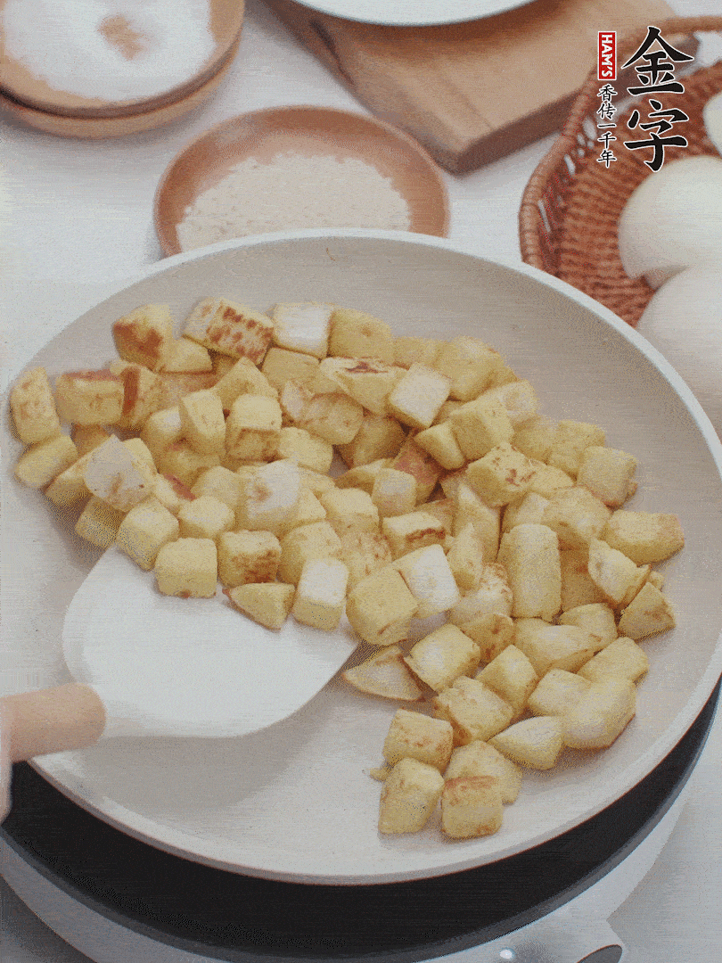 起鍋熱油，倒入饅頭丁，小火煎至蛋液凝固定型再翻面，饅頭丁部煎至金黃時(shí)盛起待用。