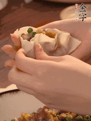 取一大勺餡料放進(jìn)餃子皮里，用大拇指按住頂部餡料，再用虎口掐出形狀。
